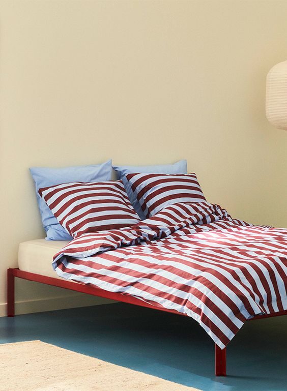 Cornflower Blue pillows on a bed with a red stripped duvet for spring