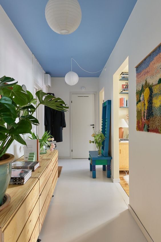 Minimalistic hallway with cornflower blue ceiling, white walls, and Scandinavian decor.