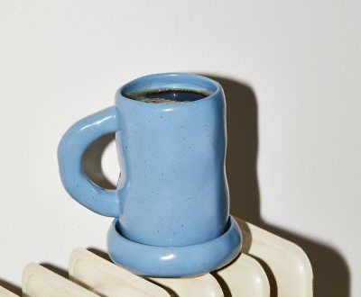 Cornflower blue ceramic coffee mug with black coffee on a white earthenware radiator.