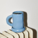 Cornflower blue ceramic coffee mug with black coffee on a white earthenware radiator.