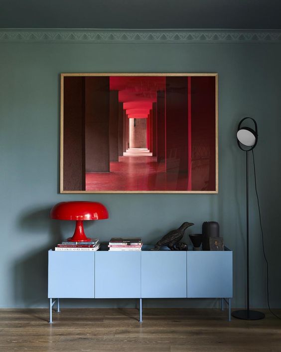 A minimalist setting with a sleek sideboard and a bold red-framed artwork, encapsulating contemporary color trends.