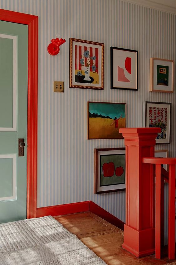 A stairway landing adorned with striking red detailing and a selection of colorful wall art that embraces current color trends.
