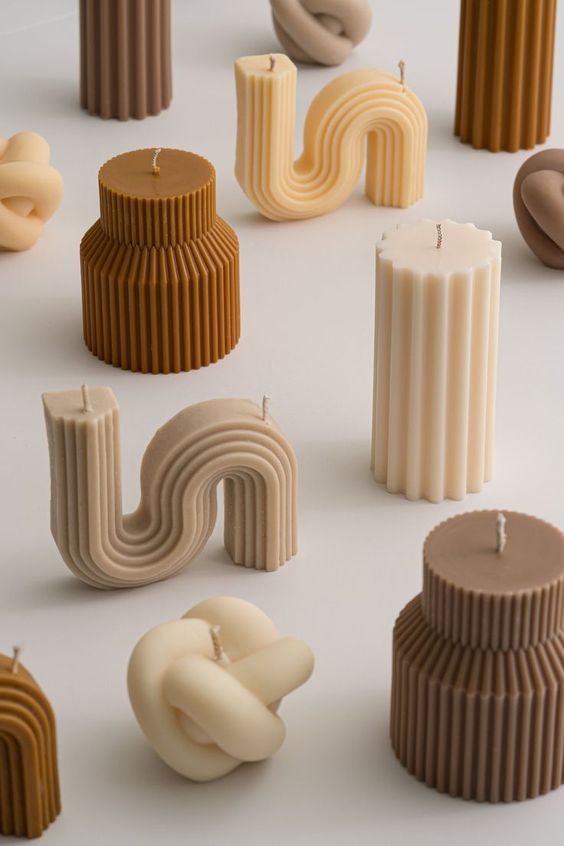 Candles shaped like simple modern sculptures in a beige and brown color palette, arranged to create a cosy atmosphere.