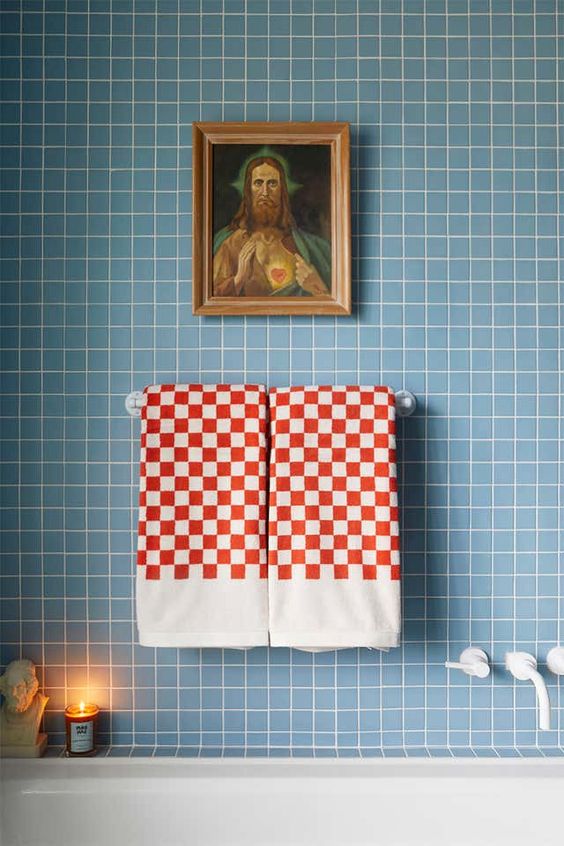 A contemporary bathroom decor with trendy checkerboard towels against a blue-tiled wall, reflecting modern color trends.