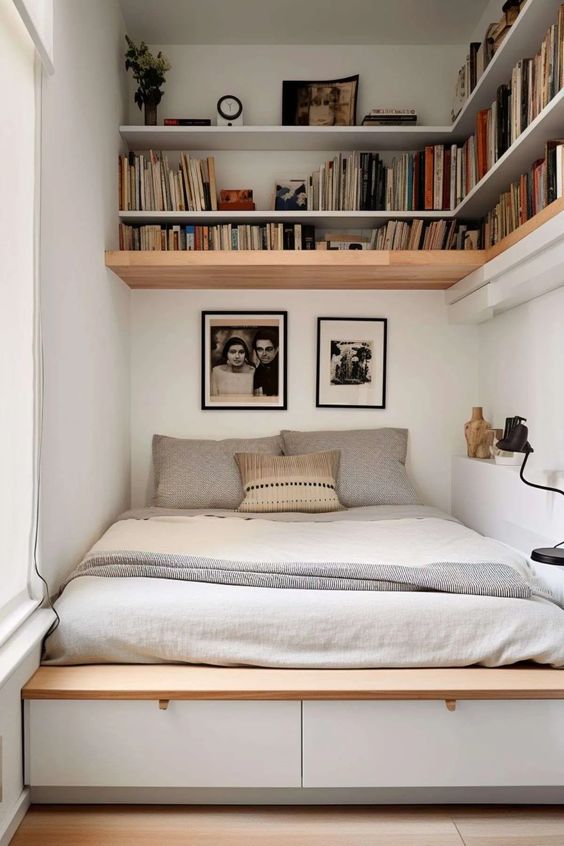 A cozy, small bedroom with a space-saving bed featuring under-bed storage drawers and overhead bookshelves.