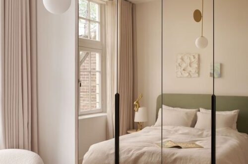 A small bedroom elegantly designed with a full-length mirrored wardrobe, creating the illusion of space.